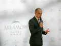 Mężczyzna w garniturze przemawia na tle logo Hotel Arłamów. Właściciel hotelu opowiada o swoich sukcesach.