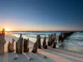 Zachód słońca nad Bałtykiem, idealne miejsce, gdzie na wakacje w lipcu. Drewniane pale na plaży.