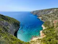 Widok na zatokę z klifami porośniętymi zielenią. Idealne miejsce na zakynthos wycieczki fakultatywne, by podziwiać turkusową wodę.