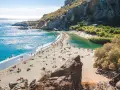 Słoneczny dzień na plaży Preveli. Ludzie odpoczywają na piasku, kąpiel w turkusowej wodzie laguny i morza.