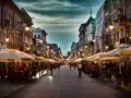 Wieczorny spacer po deptaku w mieście w województwie łódzkim nad Wartą. Ludzie siedzą w ogródkach kawiarnianych, rowerzyści przemierzają ulicę.