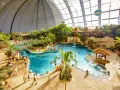 Wielki tropikalny basen pod kopułą, z palmami, wodospadami i domkami. Sprawdź nasz tropical island cennik, by zaplanować wakacje!