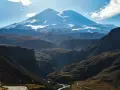 Majestatyczny Elbrus, najwyższy szczyt Europy, góruje nad doliną. Kręta droga prowadzi przez malownicze góry.