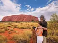 Para turystów podziwia Uluru, świętą skałę rdzennych mieszkańców Australii, w pustynnym krajobrazie.
