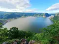 Malowniczy widok na szeroką rzekę Dunaj, otoczoną zielonymi wzgórzami i niewielką miejscowością.