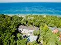 Widok z lotu ptaka na hotel otoczony lasem, z widokiem na morze. Idealne miejsce na wakacje, sprawdź nasz tui kod rabatowy!
