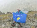 Mężczyzna z flagą najmłodszego państwa Europy, Kosowa, na szczycie góry.