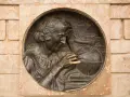 Krzysztof Kolumb, badający mapy i globus, symbolizuje jego pochodzenie i dążenie do odkryć. W tle żaglowiec.