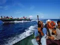 Mężczyźni z bronią na łodzi, wyglądający jak piraci, płyną w kierunku innej łodzi pełnej ludzi.