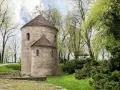 Kamienna rotunda, najstarszy kościół w Polsce, otoczona zielenią.
