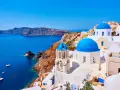 Santorini wakacje: białe domy z niebieskimi kopułami na tle turkusowego morza i klifów. Idealne miejsce na wymarzone wakacje.