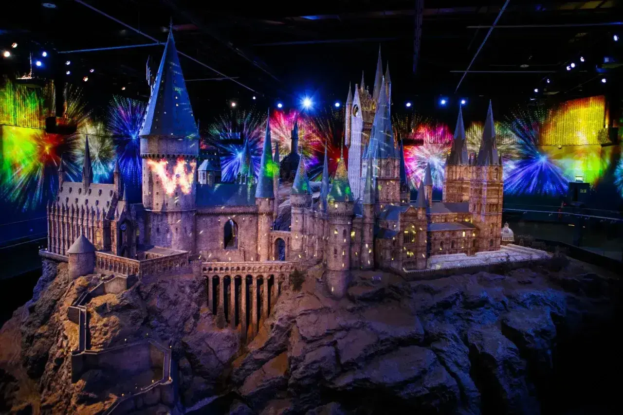 Model zamku Hogwart w muzeum Harry'ego Pottera, oświetlony magicznymi projekcjami i fajerwerkami.