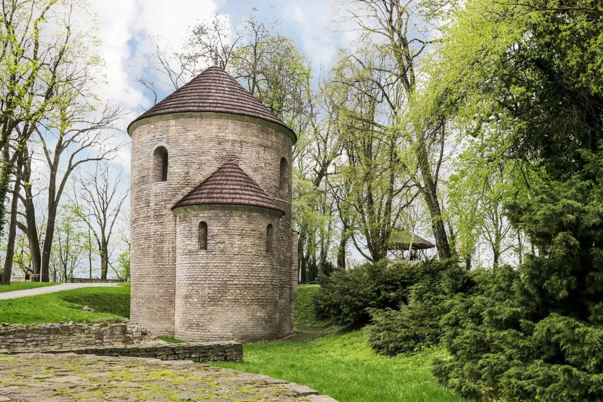 Kamienna rotunda, najstarszy kościół w Polsce, otoczona zielenią.