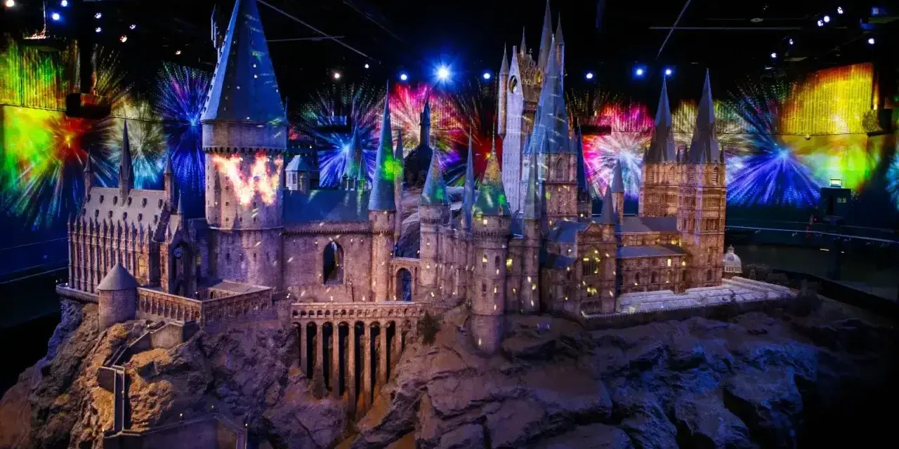 Model zamku Hogwart w muzeum Harry'ego Pottera, oświetlony magicznymi projekcjami i fajerwerkami.