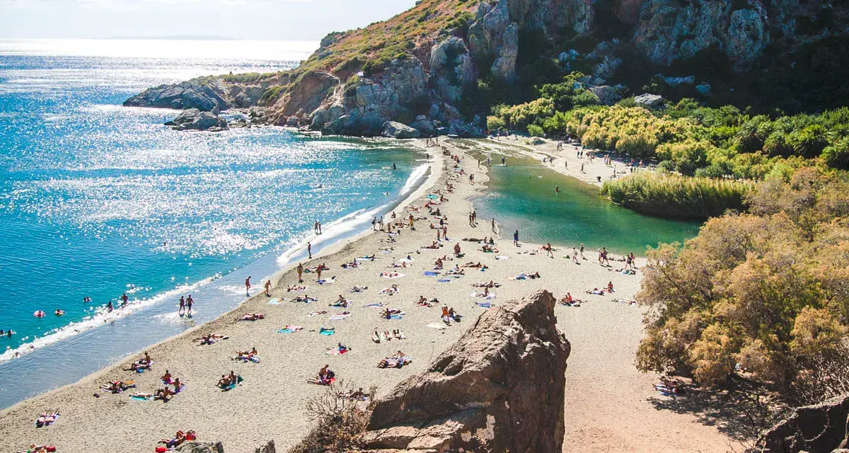 Słoneczny dzień na plaży Preveli. Ludzie odpoczywają na piasku, kąpiel w turkusowej wodzie laguny i morza.