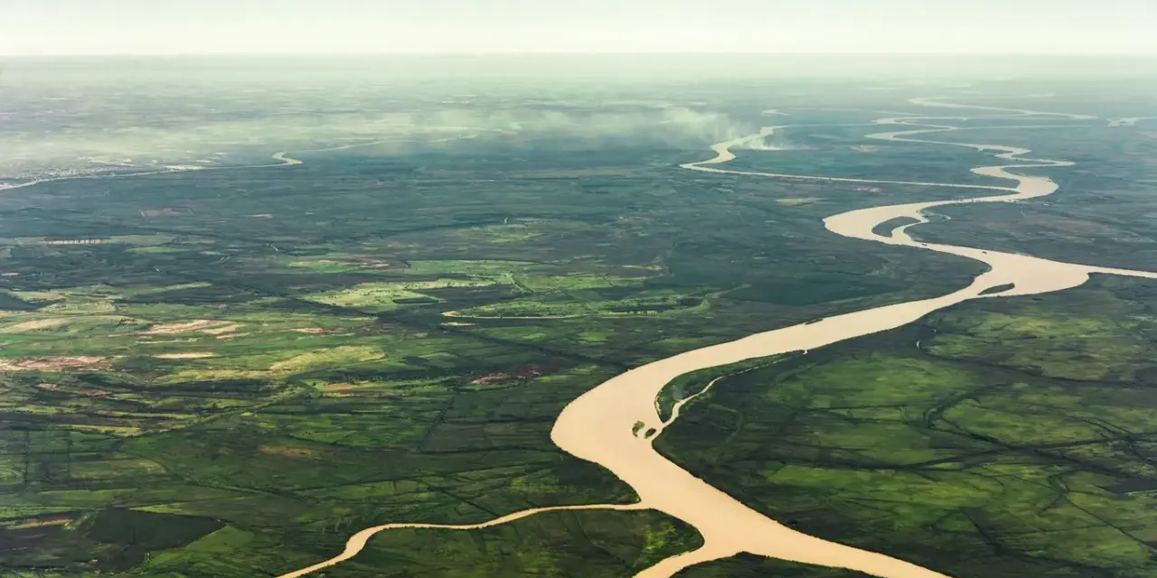 Szeroka, meandrująca amazonka rzeka przecina bujną, zieloną dżunglę, tworząc malowniczy krajobraz z lotu ptaka.