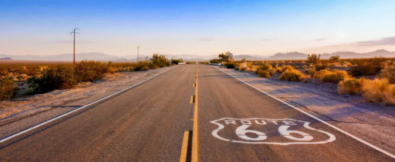 Droga Route 66 w pustynnym krajobrazie o zachodzie słońca.