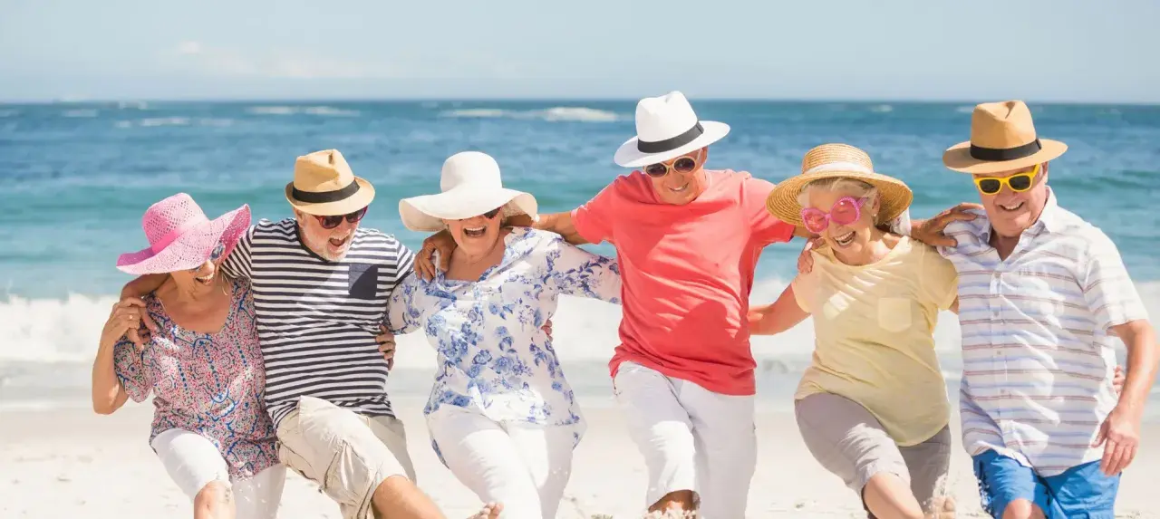 Szczęśliwi seniorzy na plaży, cieszący się słońcem i morzem. Idealne wczasy dla seniora 7 dniowe, pełne radości i wspólnych chwil.