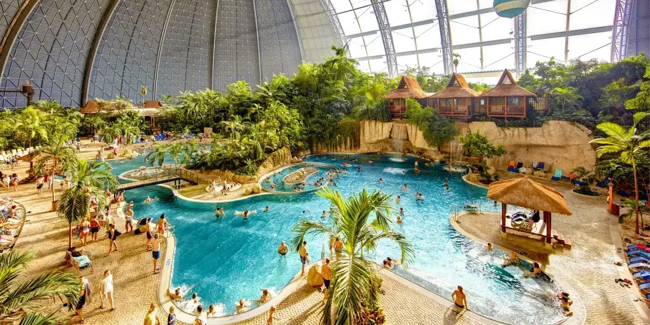 Wielki tropikalny basen pod kopułą, z palmami, wodospadami i domkami. Sprawdź nasz tropical island cennik, by zaplanować wakacje!