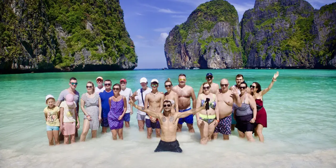Grupa ludzi cieszy się słońcem i turkusową wodą na plaży Maya Bay.