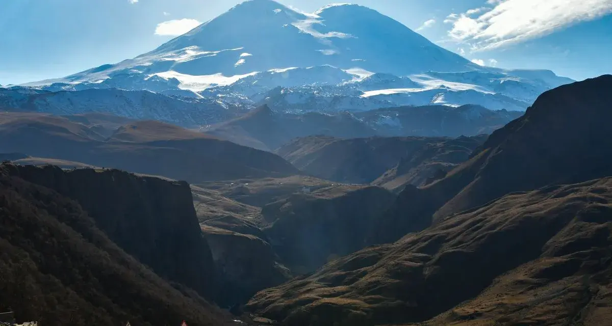 Majestatyczny Elbrus, najwyższy szczyt Europy, góruje nad doliną. Kręta droga prowadzi przez malownicze góry.