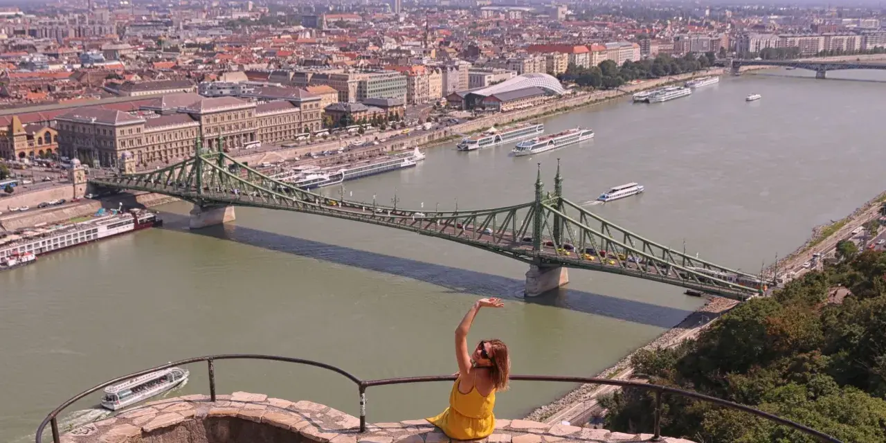 Widok na Dunaj w Budapeszcie z zielonym mostem i kobietą w żółtej sukience.