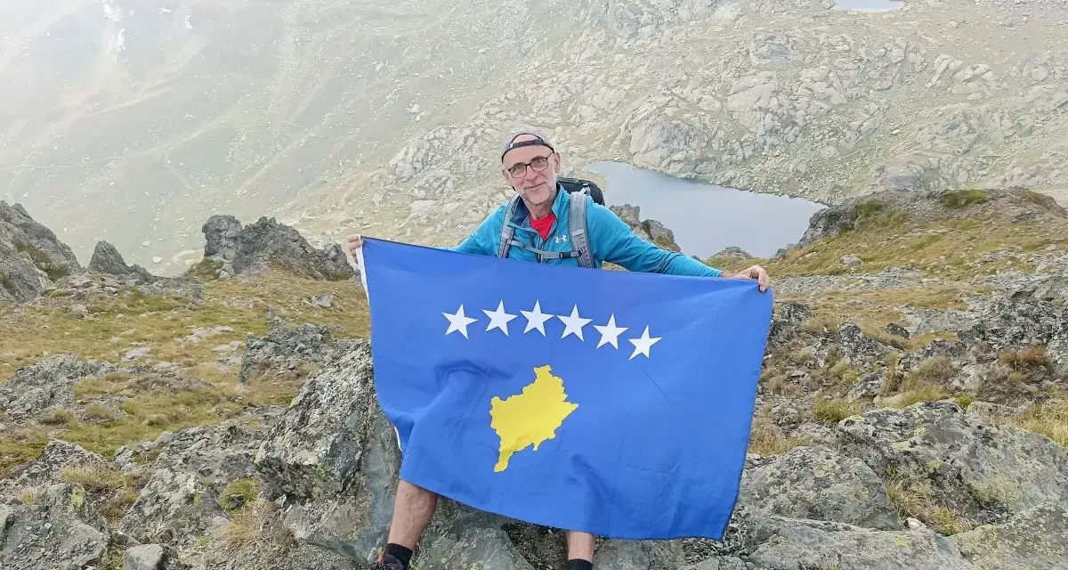 Mężczyzna z flagą najmłodszego państwa Europy, Kosowa, na szczycie góry.