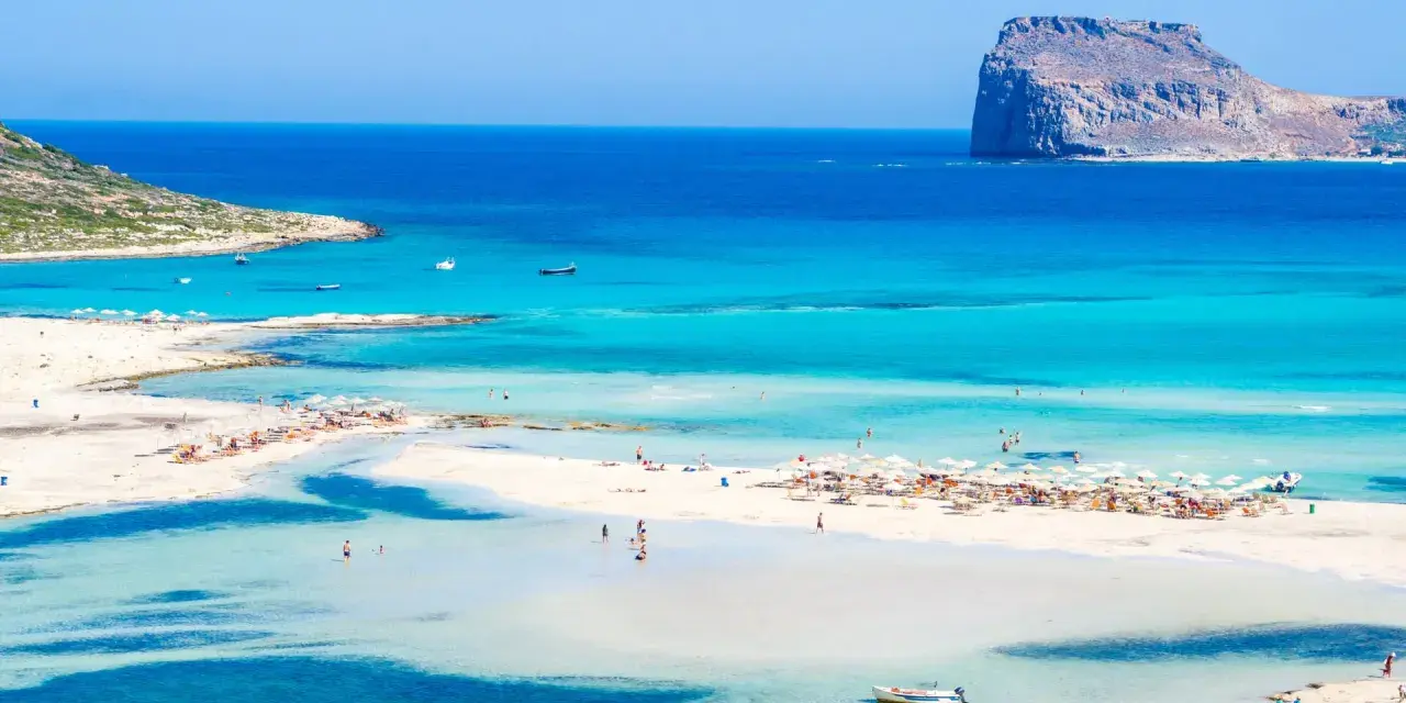 Piękna plaża z turkusową wodą i skalistą wysepką. Czy to Rodos czy Kreta?