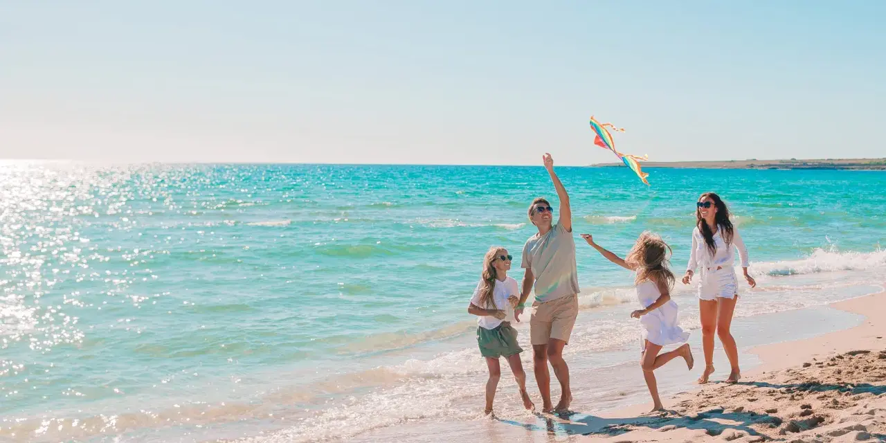 Rodzina puszcza latawiec na plaży. Idealne fajne miejsce na wakacje z dzieckiem w Polsce.