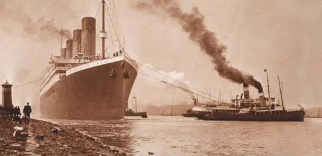 Ogromny statek, prawdopodobnie **Titanic**, wypływa z portu, holowany przez mniejsze jednostki. Dym unosi się z kominów.