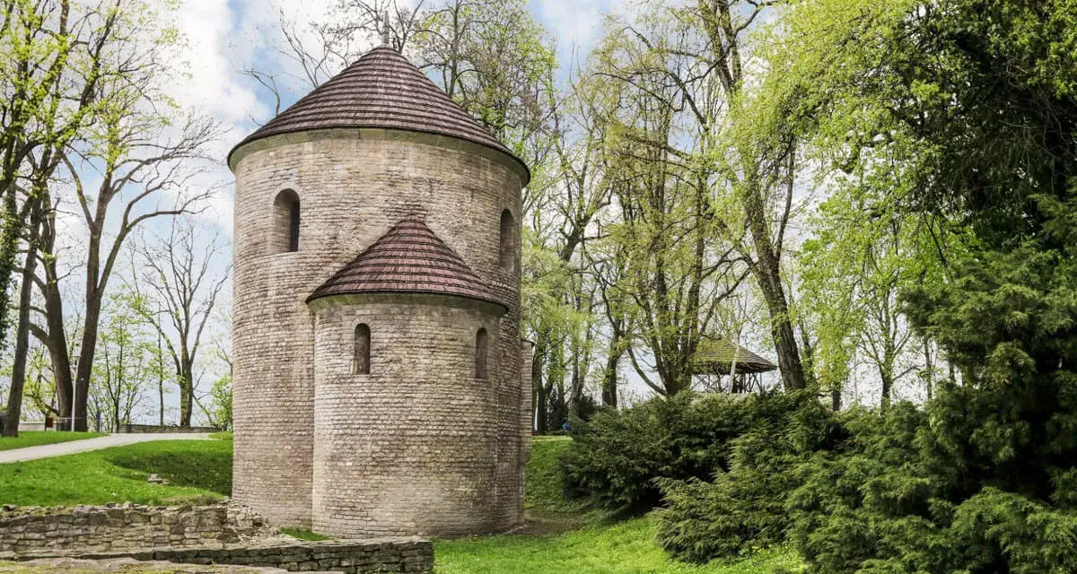 Kamienna rotunda, najstarszy kościół w Polsce, otoczona zielenią.