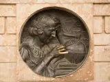Krzysztof Kolumb, badający mapy i globus, symbolizuje jego pochodzenie i dążenie do odkryć. W tle żaglowiec.