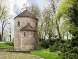 Kamienna rotunda, najstarszy kościół w Polsce, otoczona zielenią.