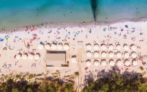 Plaża z parasolami i ludźmi, idealna na wakacje all inclusive Polska.