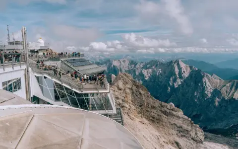 Tłum turystów na tarasie widokowym Zugspitze, najwyższego szczytu Niemiec, podziwia alpejskie krajobrazy.