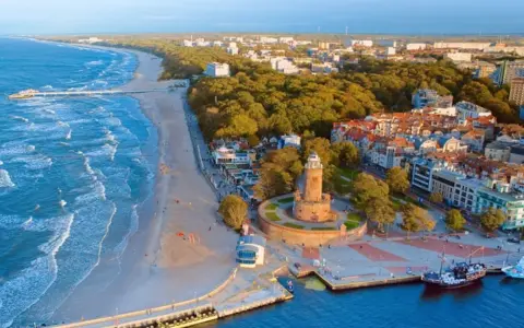 Widok na nadmorskie miasteczko z latarnią morską i plażą. Idealne miejsce na wakacje dla singli, pełne słońca i morskiej bryzy.