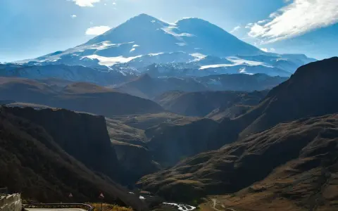 Majestatyczny Elbrus, najwyższy szczyt Europy, góruje nad doliną. Kręta droga prowadzi przez malownicze góry.