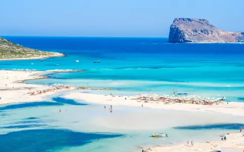 Piękna plaża z turkusową wodą i skalistą wysepką. Czy to Rodos czy Kreta?