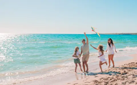 Rodzina puszcza latawiec na plaży. Idealne fajne miejsce na wakacje z dzieckiem w Polsce.