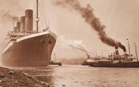 Ogromny statek, prawdopodobnie **Titanic**, wypływa z portu, holowany przez mniejsze jednostki. Dym unosi się z kominów.