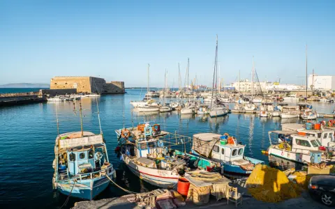 Port w Heraklionie, stolicy Krety, z łodziami rybackimi i żaglówkami cumującymi przy weneckiej twierdzy.