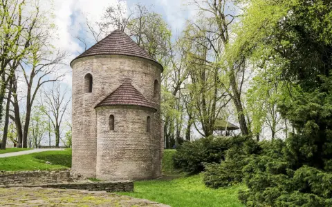 Kamienna rotunda, najstarszy kościół w Polsce, otoczona zielenią.