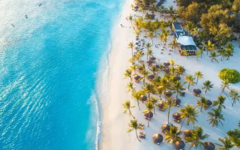 Rajska plaża na Zanzibarze z turkusową wodą, białym piaskiem, palmami i luksusowym resortem. Idealne miejsce, kiedy na Zanzibar.