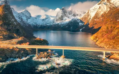 Mosty łączące wyspy w fiordach Norwegii, z ośnieżonymi górami w tle.