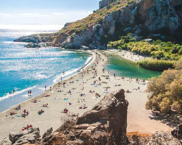 Słoneczny dzień na plaży Preveli. Ludzie odpoczywają na piasku, kąpiel w turkusowej wodzie laguny i morza.