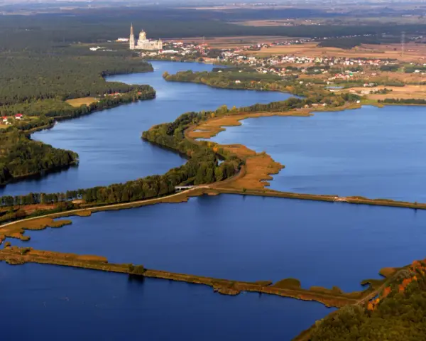 Widok z lotu ptaka na jezioro z wyspami, lasami i zabudowaniami w tle.
