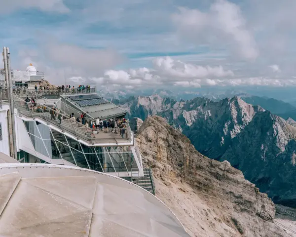 Tłum turystów na tarasie widokowym Zugspitze, najwyższego szczytu Niemiec, podziwia alpejskie krajobrazy.