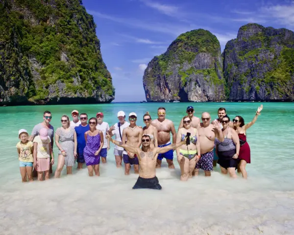 Grupa ludzi cieszy się słońcem i turkusową wodą na plaży Maya Bay.