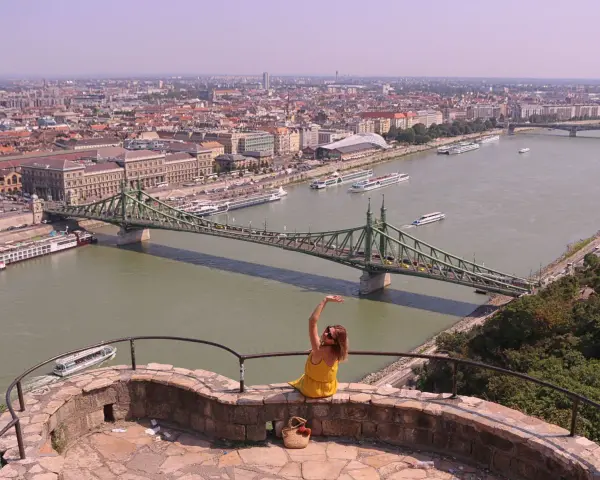 Widok na Dunaj w Budapeszcie z zielonym mostem i kobietą w żółtej sukience.
