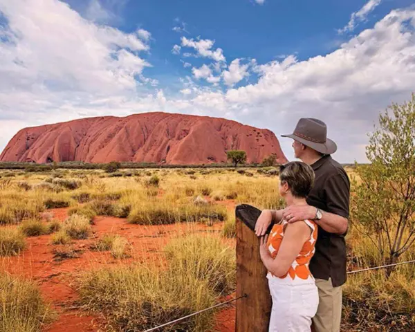Para turystów podziwia Uluru, świętą skałę rdzennych mieszkańców Australii, w pustynnym krajobrazie.